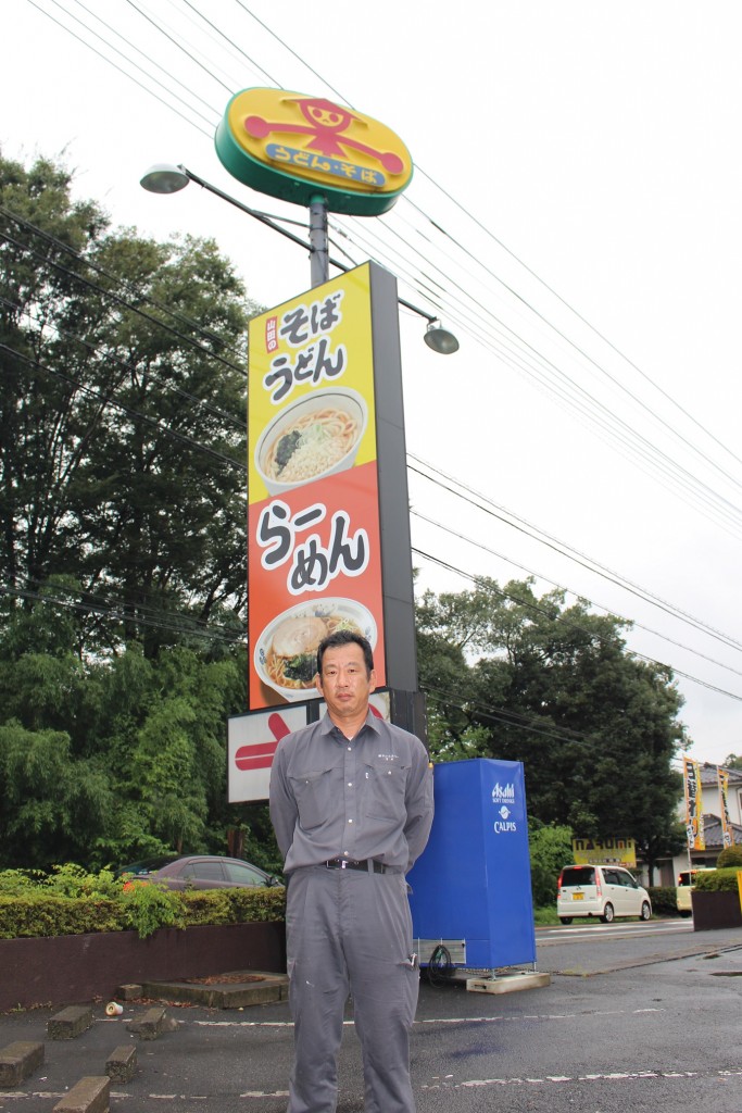 皆さん。回転看板の前に立つこの男こそ、回転看板の立役者みやさんだ。回転看板を背負って早１０年！